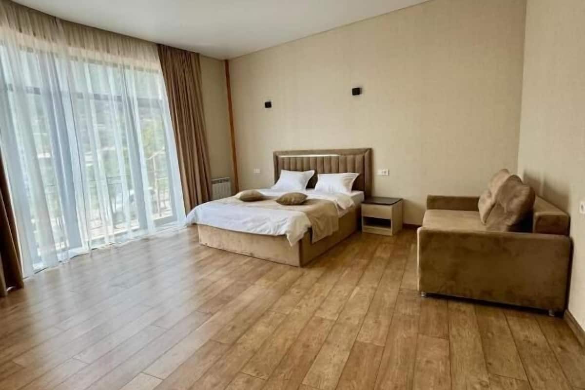 Un'ampia camera da letto con un letto grande, una poltrona e vista panoramica da finestre a tutta parete.
