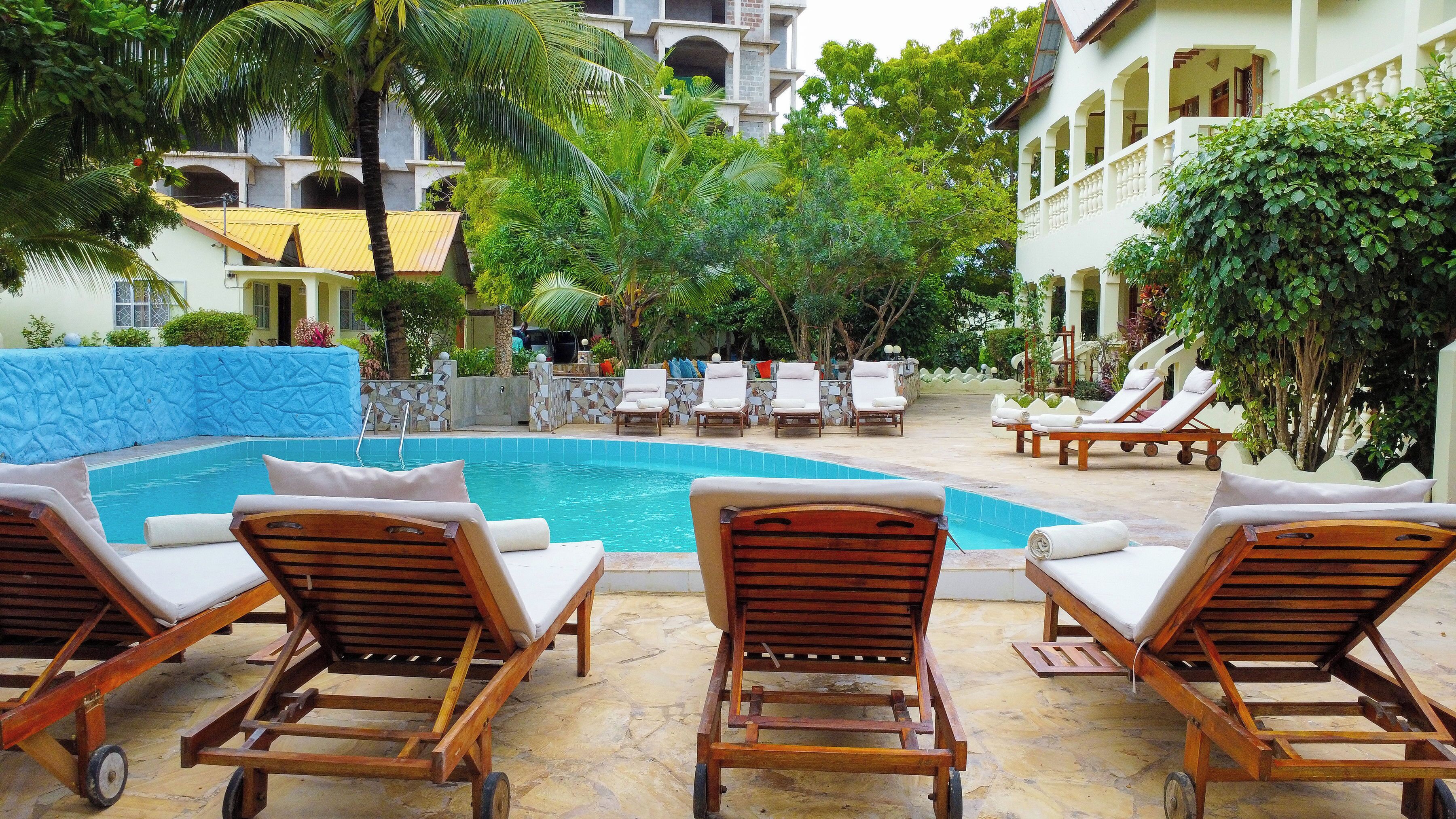 A pool area with lounge chairs and a stone wall.
