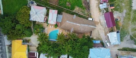 An aerial view of a residential area with a swimming pool, multiple houses, and a road.