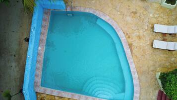 A rectangular pool with a curved edge, surrounded by a stone deck.