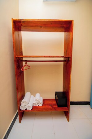 Un estante de madera con toallas enrolladas y una caja negra.