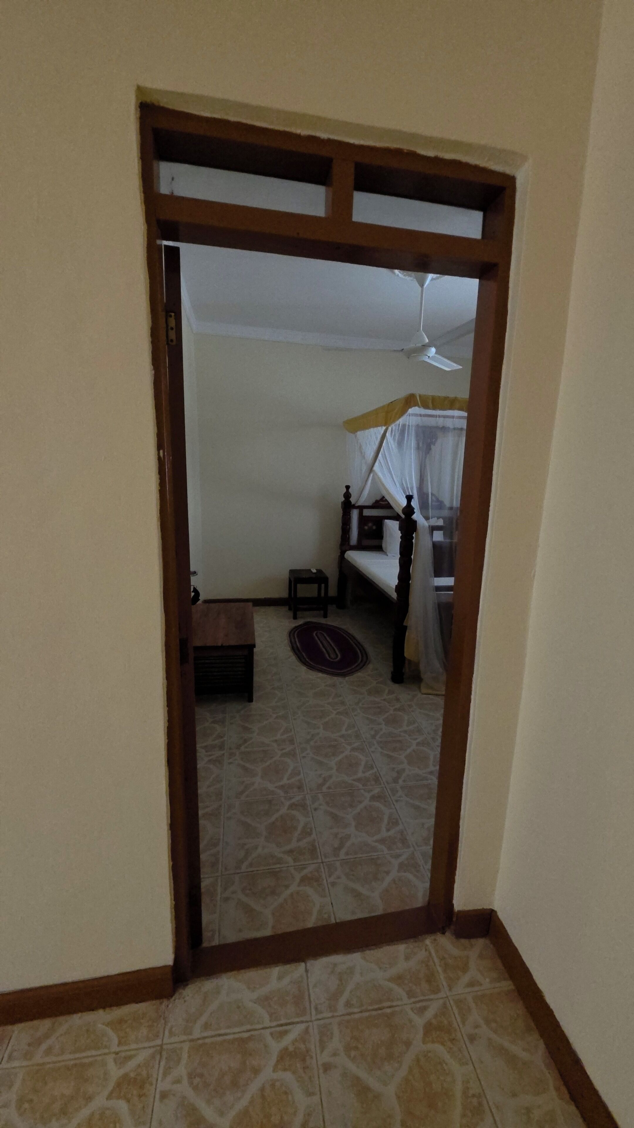 Una habitación con cama, una mesita y un ventilador de techo.