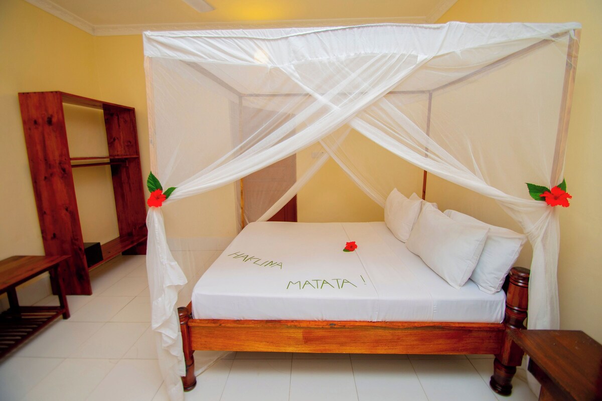 A bed with a canopy, a wooden bench, and a shelf unit.