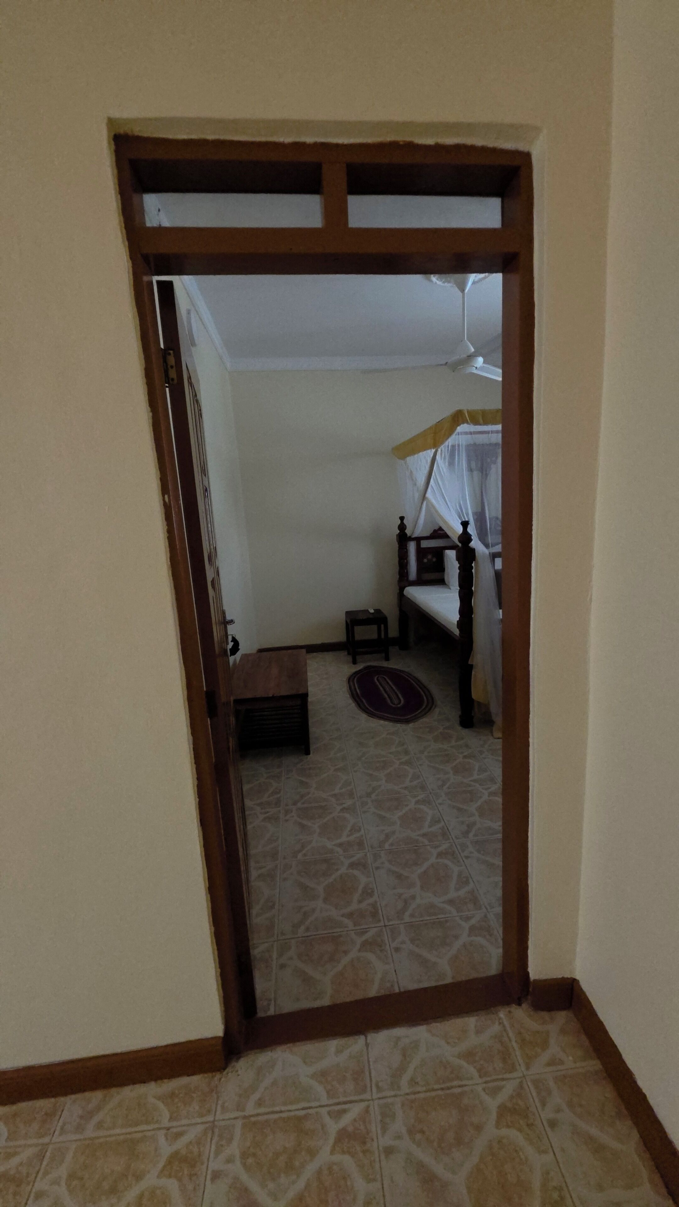A room with a bed, a small table, and a ceiling fan.