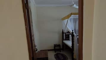 A room with a bed, a small table, and a ceiling fan.
