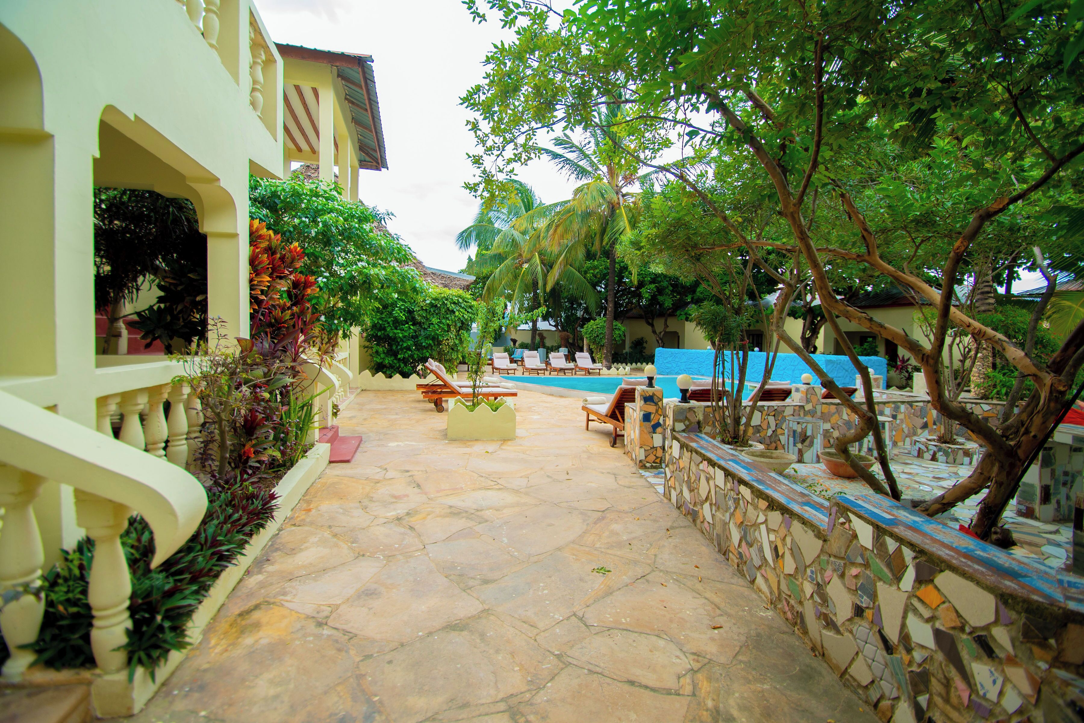 Un cortile con piscina, sedie a sdraio e un muro in pietra.