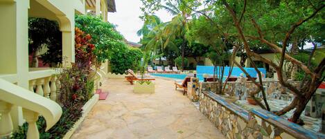 A courtyard with a swimming pool, lounge chairs, and a stone wall.