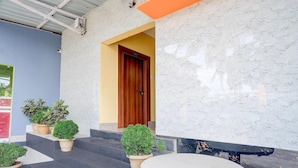 A building entrance with a wooden door, potted plants, and a marble wall. - Saver Single Hotel Aniruddha Grand (Guwahati)