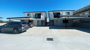 A modern two-story house with a garage, parked cars, and a clear blue sky. - 262Troughton (Coopers Plains)