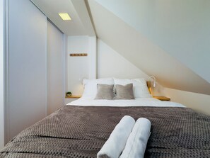 A modern bedroom with a bed, pillows, a bedside table, a lamp, and a wall-mounted shelf. - Mountain Retreat in Jáchymov (Jáchymov)