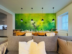 A dining area with a green textured wall, wooden table, and four pendant lights. - Mountain Retreat in Jáchymov (Jáchymov)