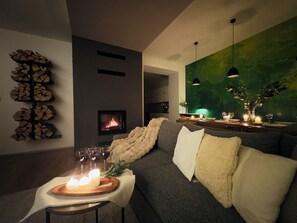 A modern living room with a fireplace, a sofa with cushions, a dining table with glasses, and a green wall. - Mountain Retreat in Jáchymov (Jáchymov)