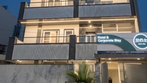 A multi-story hotel with balconies, a sign indicating 'Hotel & Corporate Stay,' and a modern architectural design. - Shft-In Hotel (Noida)