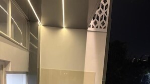 A balcony with a table and chair, a view of the night sky, and a railing. - Shft-In Hotel (Noida)