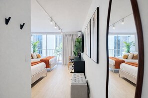 Ein modernes Hotelzimmer mit zwei Betten, einem Schreibtisch und großen Fenstern.