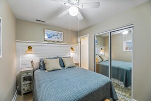 Ein Schlafzimmer mit einem Bett, Nachttischen, einem Deckenventilator und einem Spiegel.