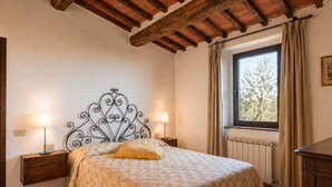 A bedroom with a bed, nightstands, a window with curtains, and a radiator. - Romantic Tuscan Retreat With Pool (Castelnuovo Berardenga)
