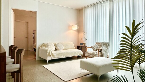 A modern living room with a sofa, ottoman, and a dining area with chairs.