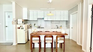 A modern kitchen with white cabinets, a wooden dining table, and four chairs.