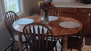 A dining area with a wooden table, chairs, a vase with flowers, a chandelier, and wooden cabinets. - Serene 2-bedroom bed & breakfast in charming Saugerties (Saugerties)
