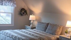 A bedroom with a large bed, two bedside tables with lamps, a window with curtains, and a patterned rug. - Serene 2-bedroom bed & breakfast in charming Saugerties (Saugerties)