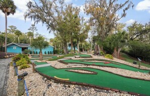 Een minigolfbaan met een huis op de achtergrond.
