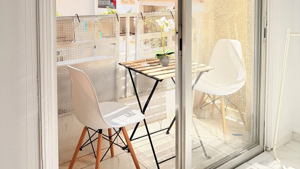 Una habitación moderna con un divisor de vidrio corredizo que da a un espacio exterior con una mesa y sillas.