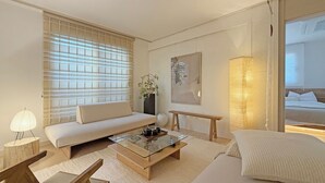 A modern hotel room with a sofa, a glass coffee table, a bedside table, a lamp, a potted plant, and a bed. - Family-sized | Premium Stay | Near Incheon Airport | 5 minutes to Unseo Station (Incheon)