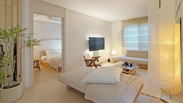 A hotel room with a bed, a sofa, a TV, a lamp, a small table, and a potted plant. - Family-sized | Premium Stay | Near Incheon Airport | 5 minutes to Unseo Station (Incheon)