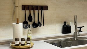 A kitchen with a hanging utensil rack, a paper towel holder, a soap dispenser, and a salt and pepper set on a wooden tray. - Family-sized | Premium Stay | Near Incheon Airport | 5 minutes to Unseo Station (Incheon)
