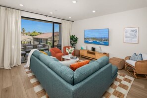 Ein modernes Wohnzimmer mit einer Couch, Sesseln, einem Couchtisch und einem Fernseher.