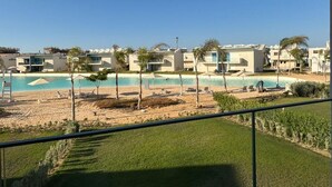 A hotel with a pool, beach chairs, and palm trees. - Fouka North Coast CL9-CH22-01 (Marsa Matrouh)