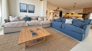 A living room with two sofas, a coffee table, and a kitchen in the background. - Fouka North Coast CL9-CH22-01 (Marsa Matrouh)
