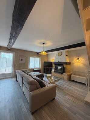 A living room with a sofa, a TV, a fireplace, and a wooden ceiling beam. - Liorelys en Provence - Charming house with swimming pool (L'Isle-sur-la-Sorgue)