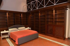 Ein Schlafzimmer mit einem Bett, Nachttischen, einem Bücherregal und einem Holzschrank.