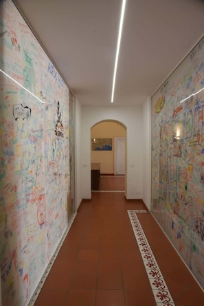 Ein Flur mit weißen Wänden, bedeckt mit bunten Graffiti-Sprühen, der zu einem Raum mit einer Karte an der Wand führt.