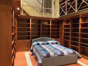 A bedroom with a bed, built-in shelving, and a view of the upper floor. - The Supreme Penthouse Iconic Terrace in Old Naples (Napoli)