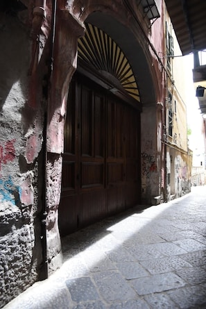 A narrow street with a large wooden door under an arched structure. - The Supreme Penthouse Iconic Terrace in Old Naples (Napoli)