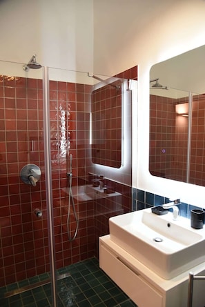 A bathroom with a glass-enclosed shower, a white sink, and a mirror above it. - The Supreme Penthouse Iconic Terrace in Old Naples (Napoli)
