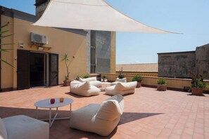 A rooftop terrace with outdoor seating, a table, and potted plants. - The Supreme Penthouse Iconic Terrace in Old Naples (Napoli)