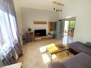 Een moderne woonkamer met een flatscreen televisie, een bank, een salontafel en een eethoek.