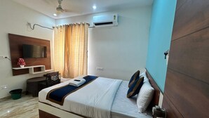 A hotel room with a bed, a TV, an air conditioner, a desk, and a chair. - S K Comforts Rooms (Bengaluru)