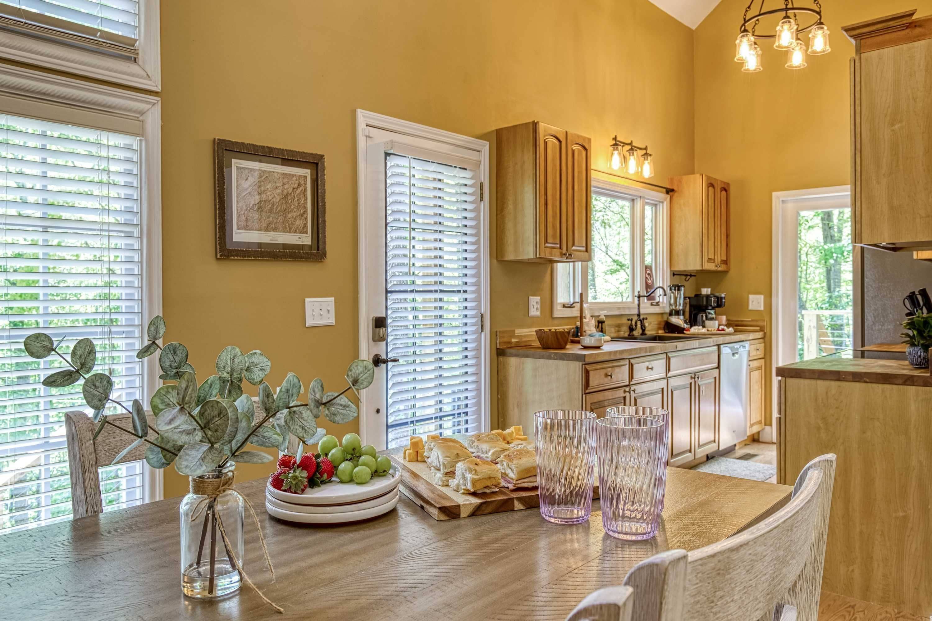 A kitchen with wooden cabinets, a dining table with chairs, and a vase with greenery.