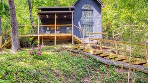 Een chalet met een houten terras, een trap en een groot raam.