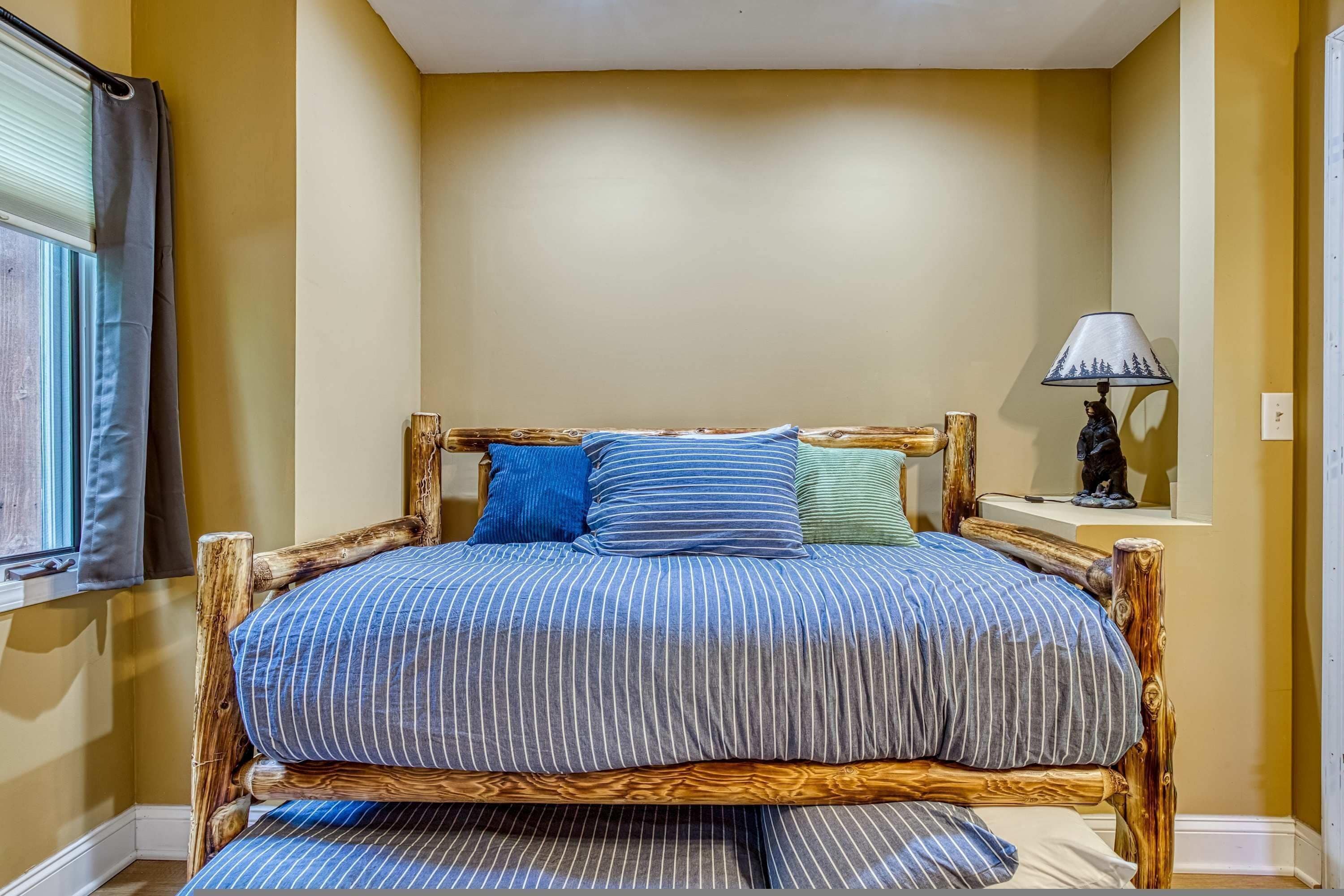 Un lit avec une couvre-lit à rayures, une tête de lit en bois et une table de chevet avec une lampe.