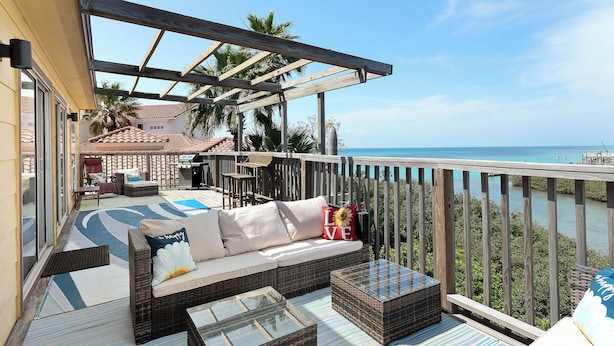 A covered outdoor seating area with a sofa, cushions, and a coffee table. - Large Family Condo w/ Private Balcony Overlooking the Bay! (South Padre Island)