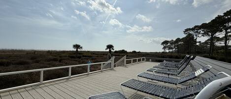 A wooden deck with lounge chairs and a railing overlooking a natural landscape.