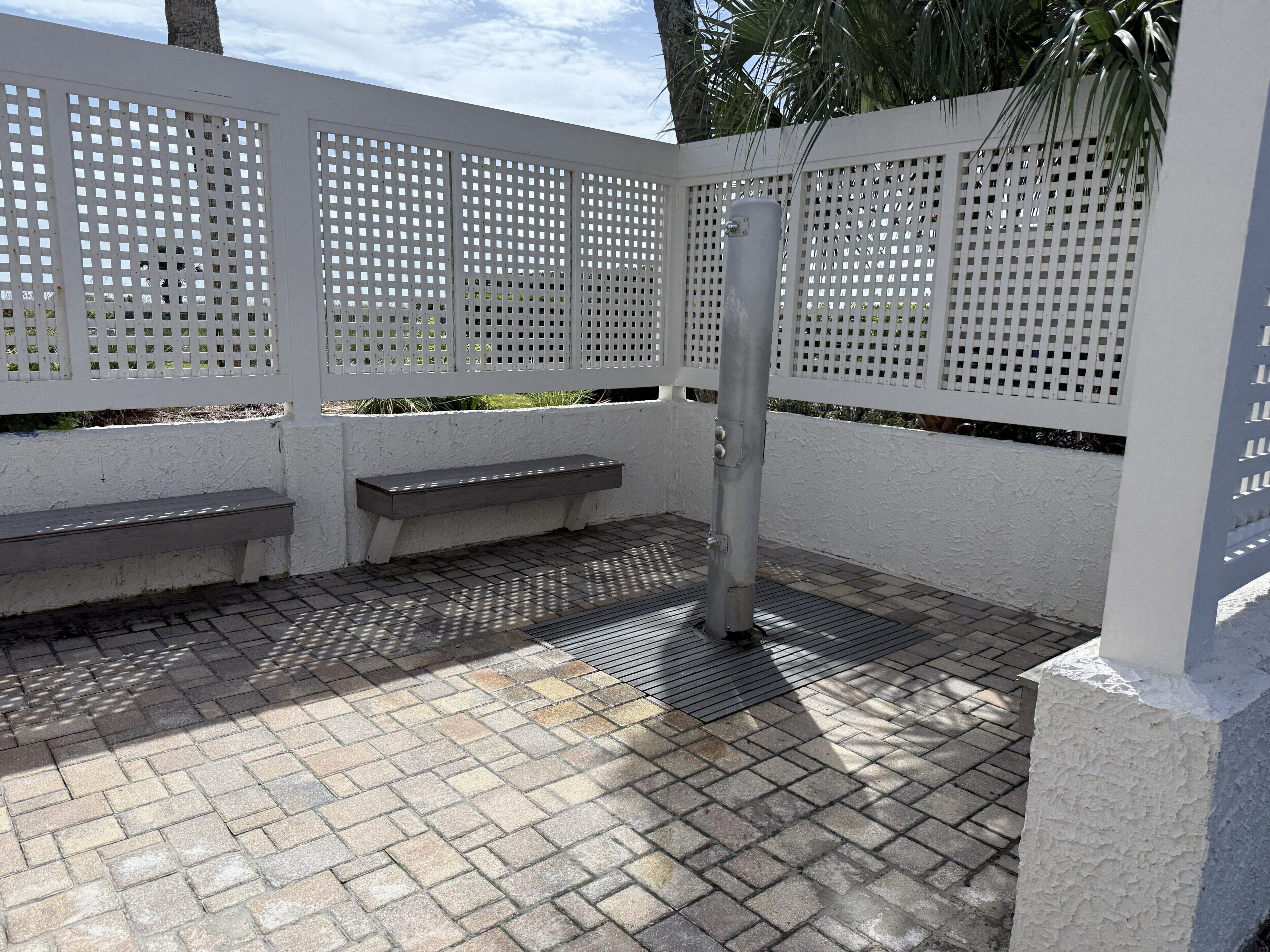 Eine Terrasse mit weißem Zaun, einem Metallpfosten und einer Bank.