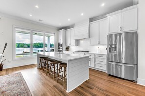 Una cocina moderna con armarios blancos, un refrigerador de acero inoxidable y una isla grande con taburetes de bar.