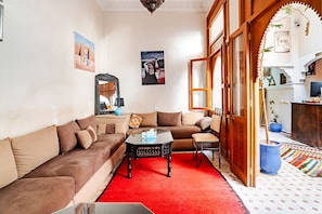 Uma sala de estar com um sofá, uma mesa de centro e um tapete vermelho.